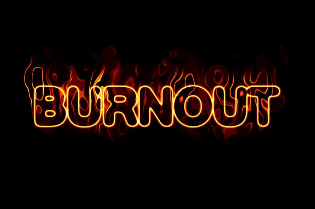 Black background with the word Burnout in neon letters and flames. This is to signify that Burnout and Imposter Syndrome are often linked.
